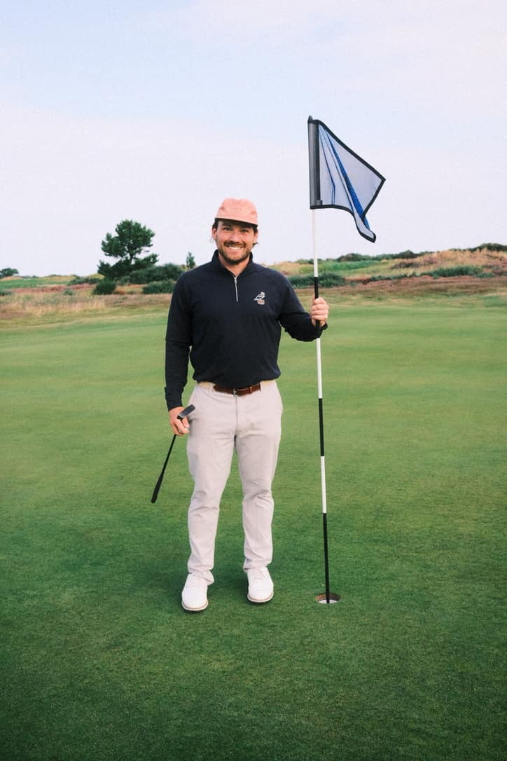 Greg Egan holding a flagstick on a golf green