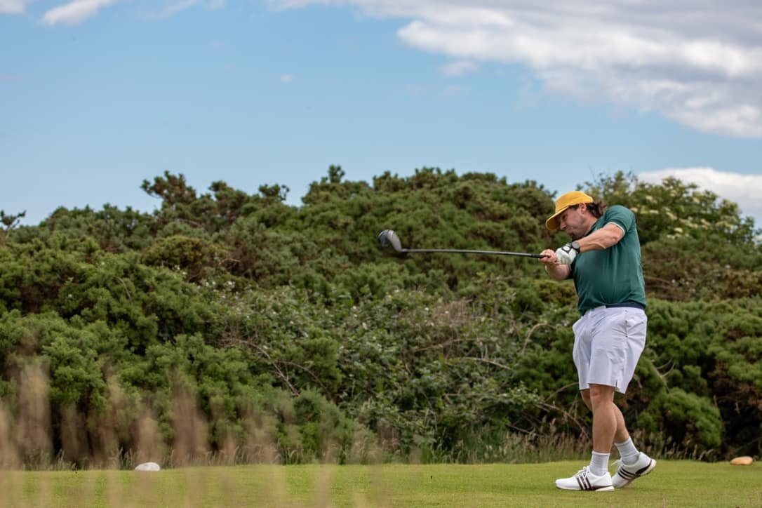 Greg Egan swinging a golf club from a tee