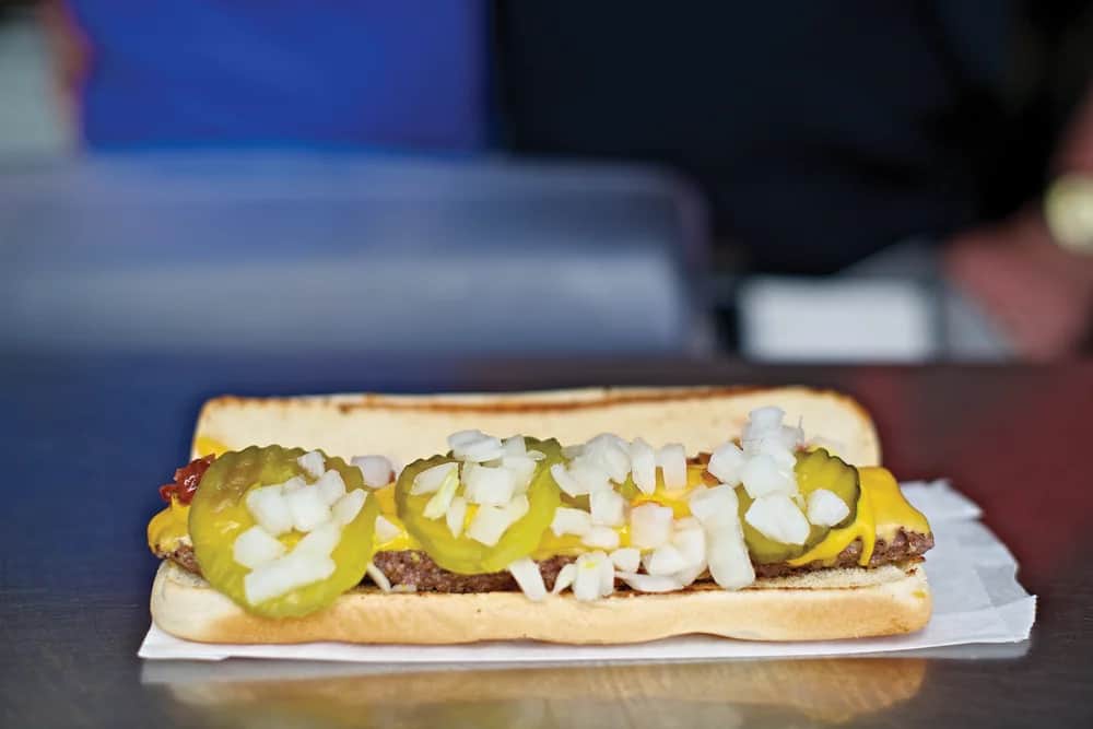A fully loaded Burgerdog with cheese, pickles, onions, and condiments. Photo courtesy of Hot Dog Bills, from the official Hot Dog Bills photo gallery.