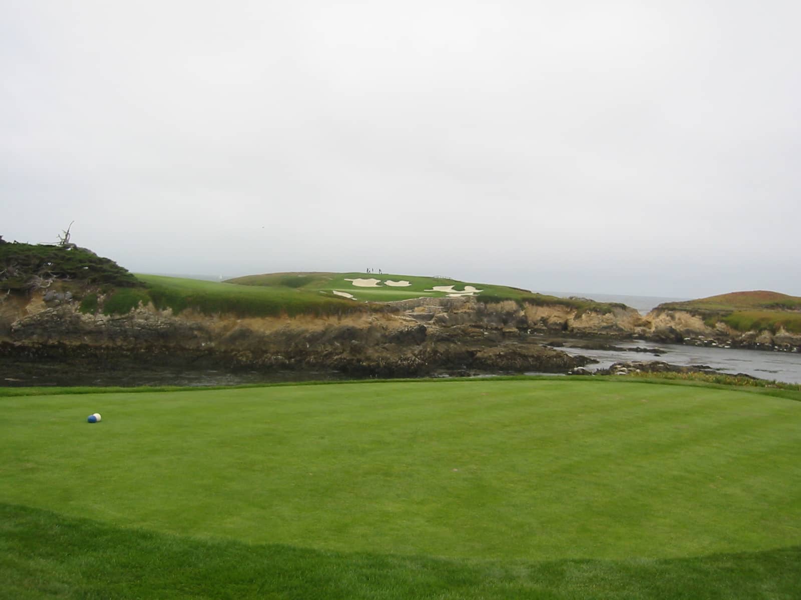 The tee box of the iconic par-3 16th hole at Cypress Point Club, playing across the Pacific Ocean. Photo by schnaars (San Jose, CA), via Flickr / Wikimedia Commons, licensed CC BY-SA 2.0.