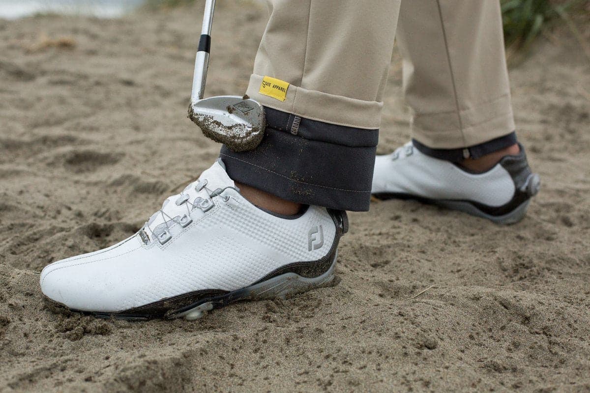 A golfer uses the integrated wiping cuff on State Apparel Competition Pants to clean a sandy wedge. Photo courtesy of State Apparel, from the official brand homepage: https://stateapparel.com/